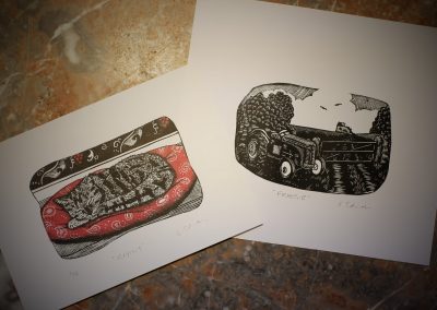 two lino prints of a feruson tractor and a cat asleep on a paisley cushion.
